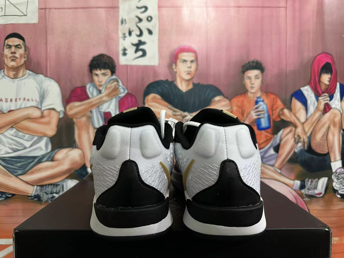 Rear view of a pair of white and black basketball shoes with gold-tone details