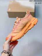 Side profile showing the textured upper, On branding, orange midsole, and rugged outsole.