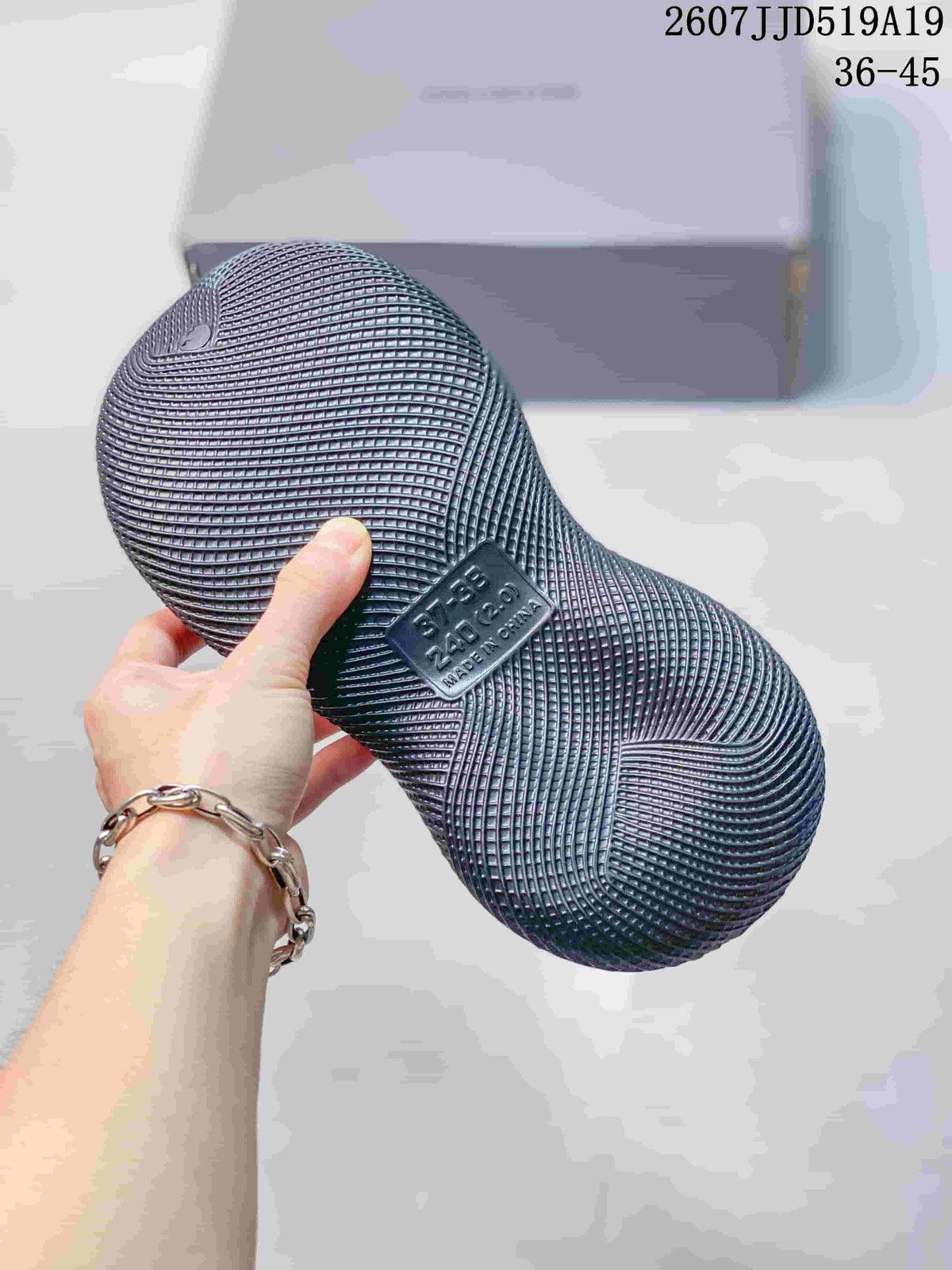 Side view of a gray molded clog showing its textured upper, ventilation holes, and raised sole; style code and size range are visible in the upper right.