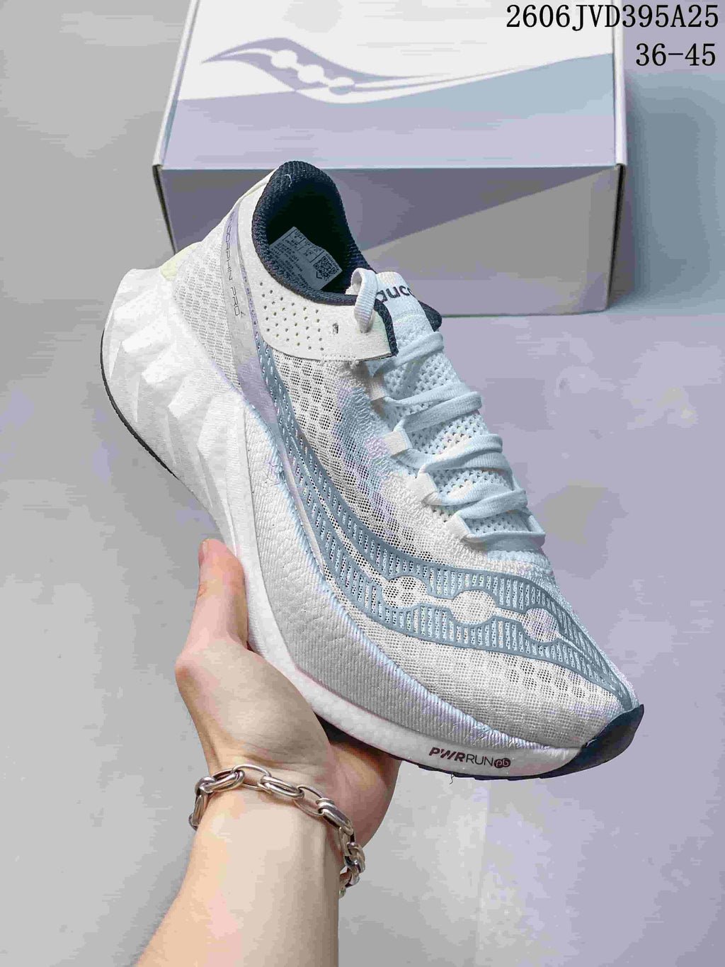 Close-up of a white Saucony running shoe with pale blue-gray details and a sculpted midsole; image text states 36–45.