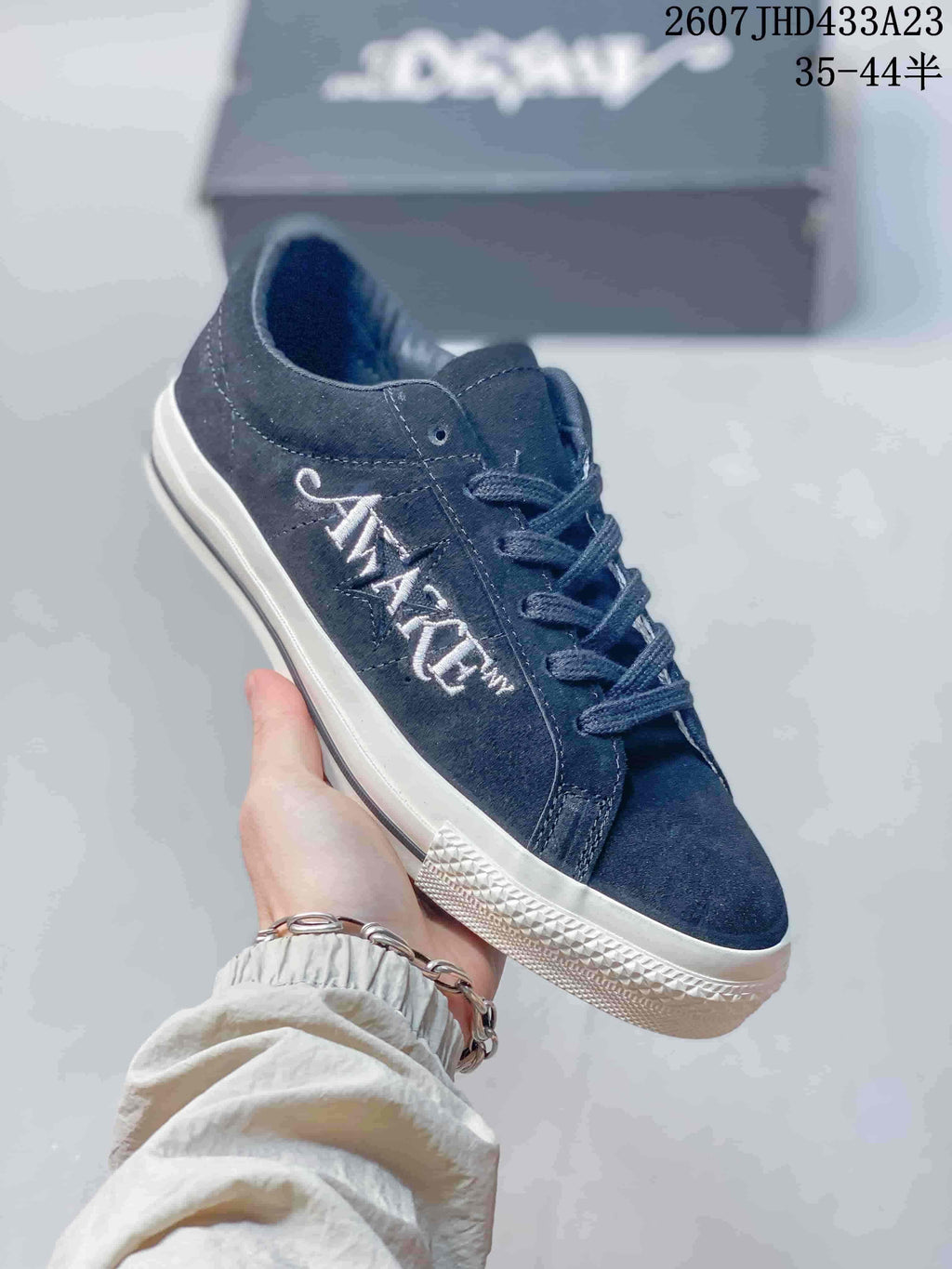 Angled side view of one dark navy low-top sneaker with white side embroidery.
