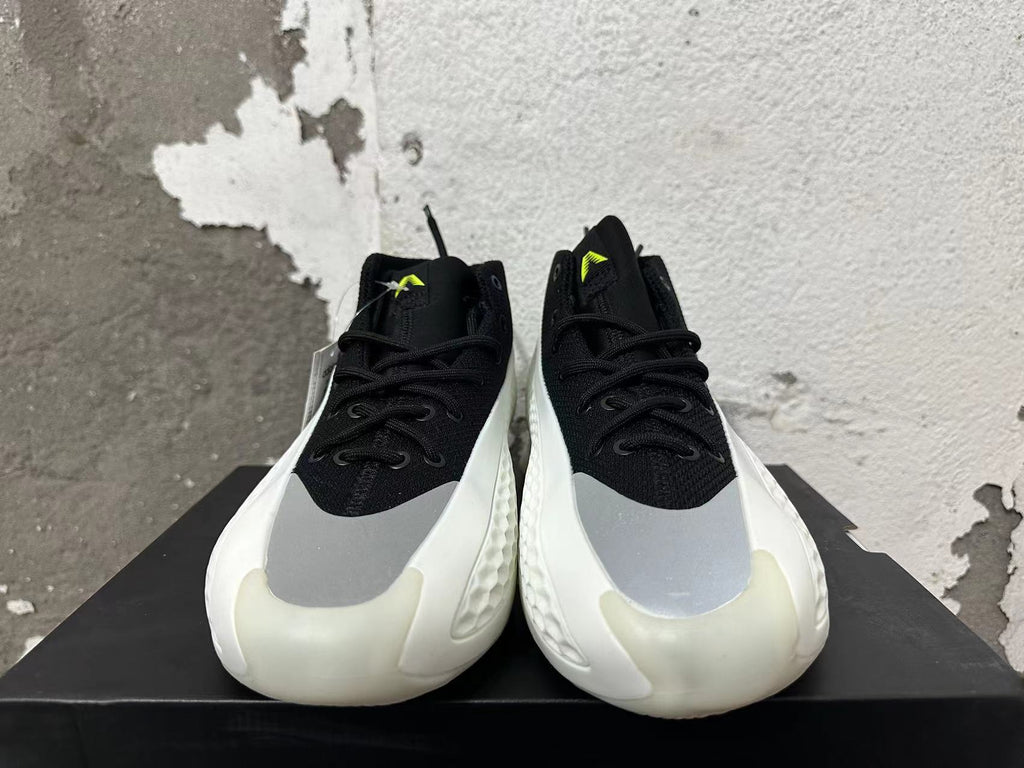 Front view of black lace-up basketball shoes with gray forefoot panels and neon-green tongue details.