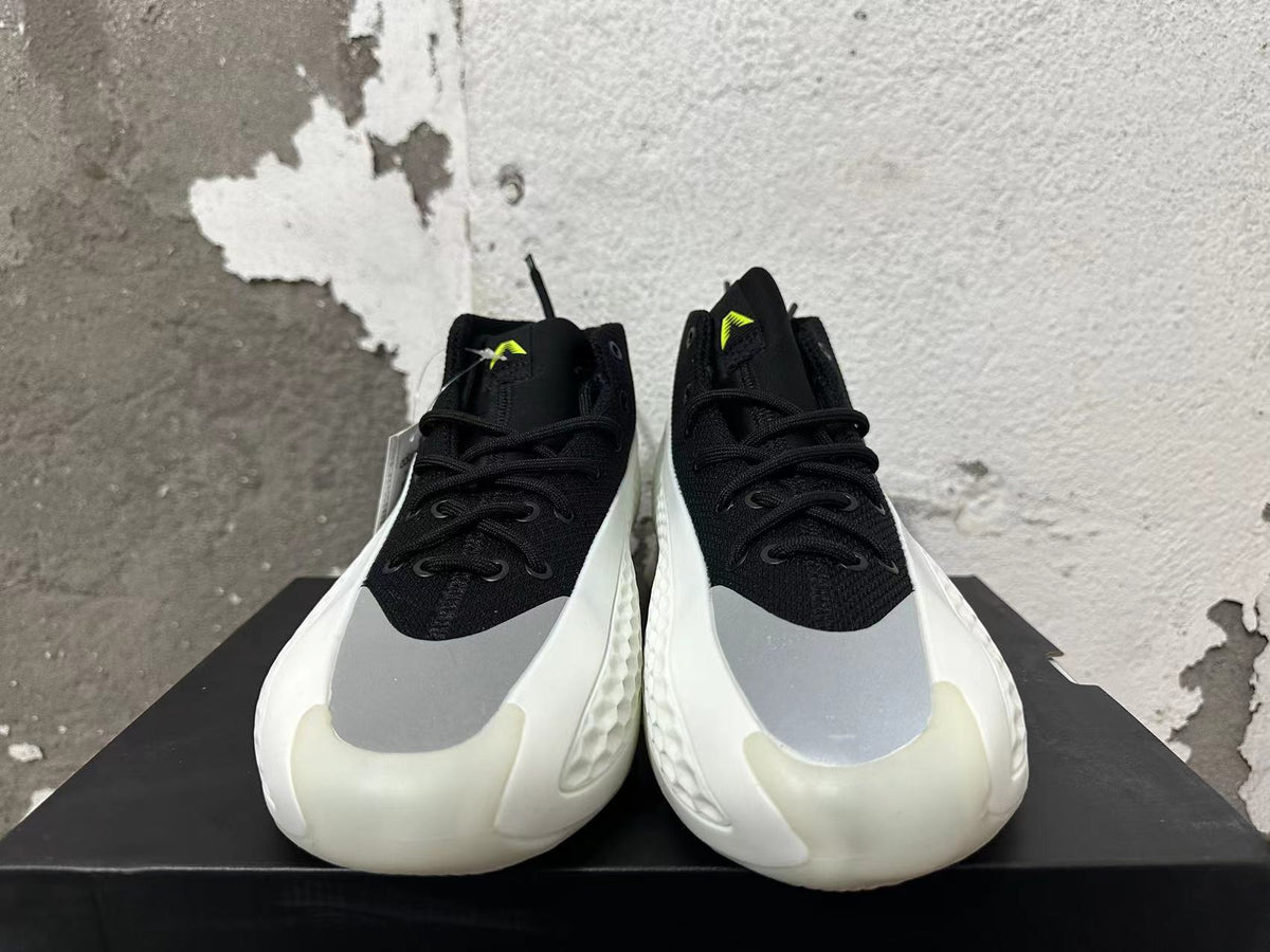 Front view of black lace-up basketball shoes with gray forefoot panels and neon-green tongue details.