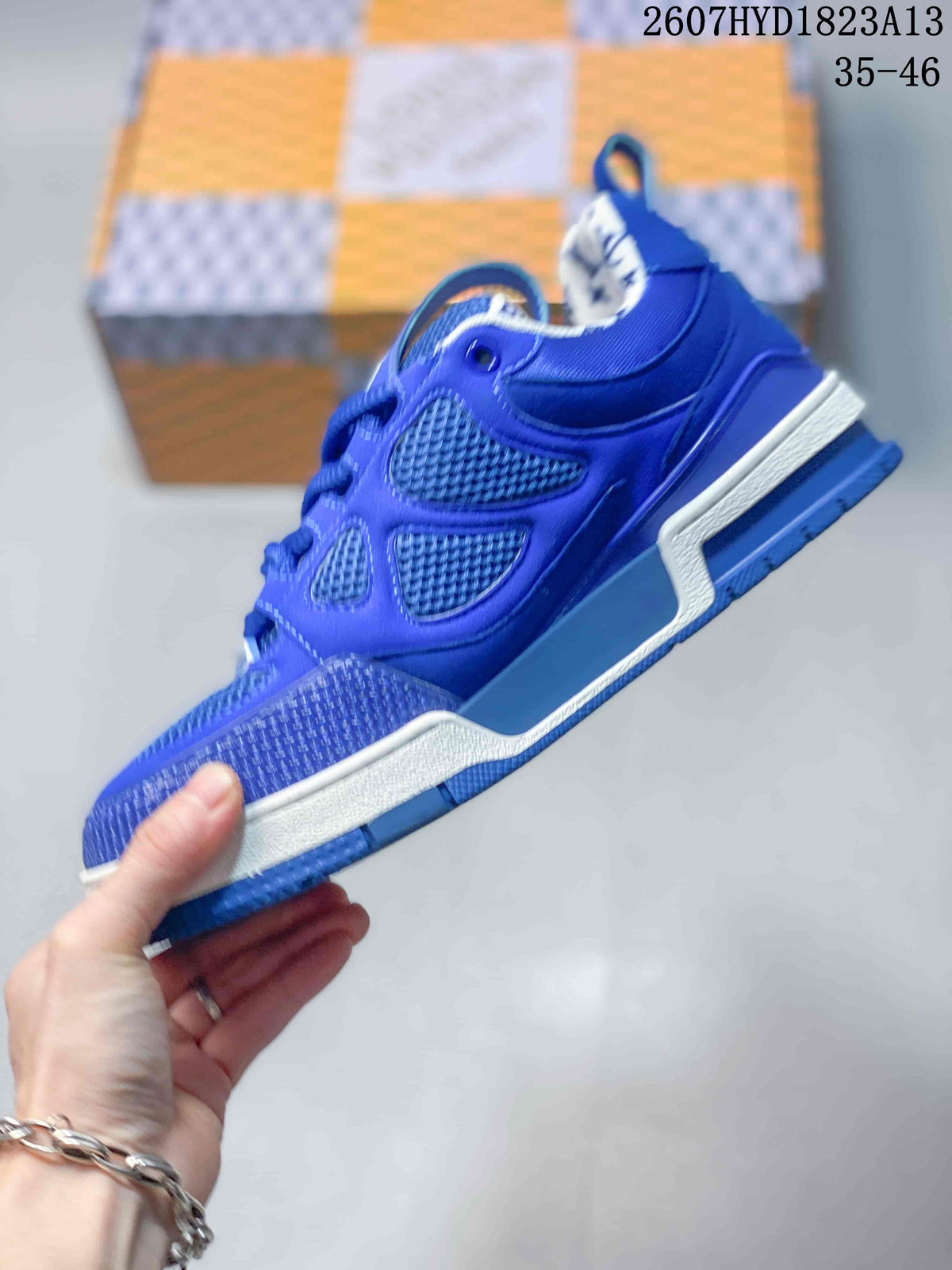 Side profile of a blue Louis Vuitton Trainer sneaker showing layered panels, mesh sections, and the contrasting midsole.