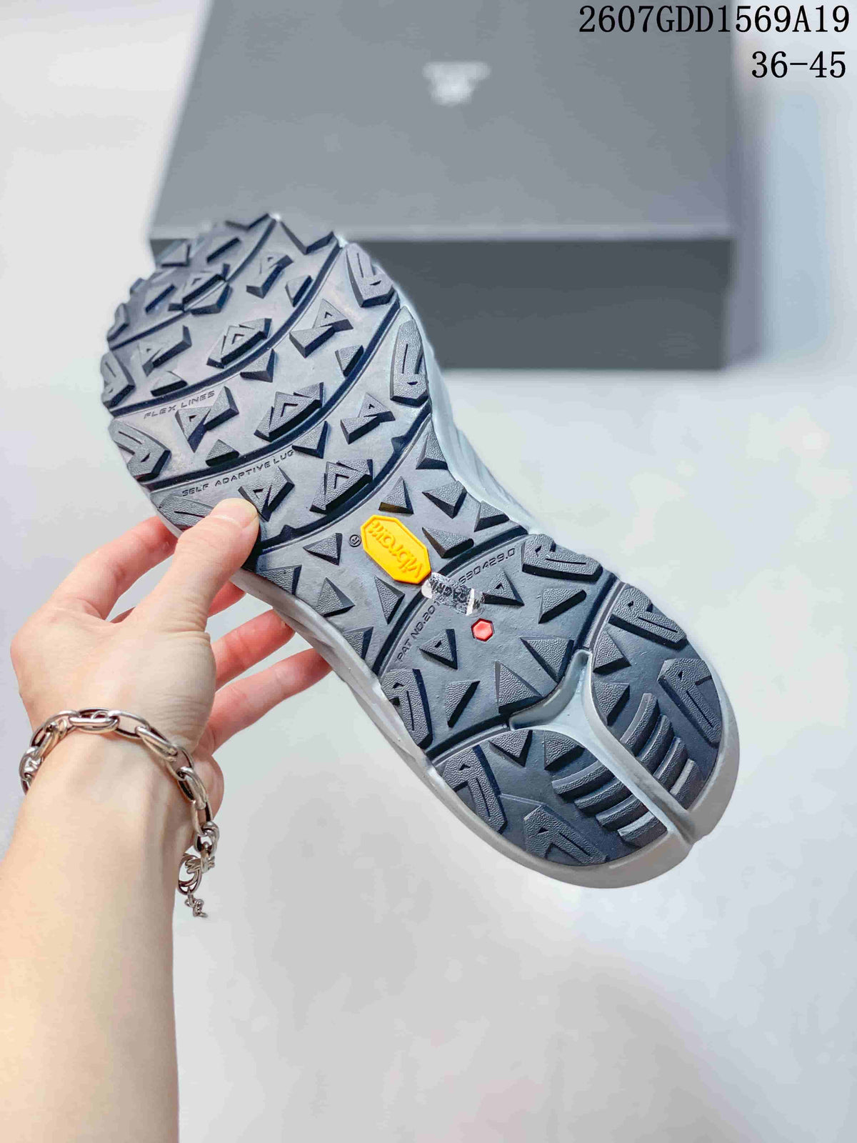 Close-up of the shoe outsole showing a deep directional lug pattern and a yellow outsole insert.