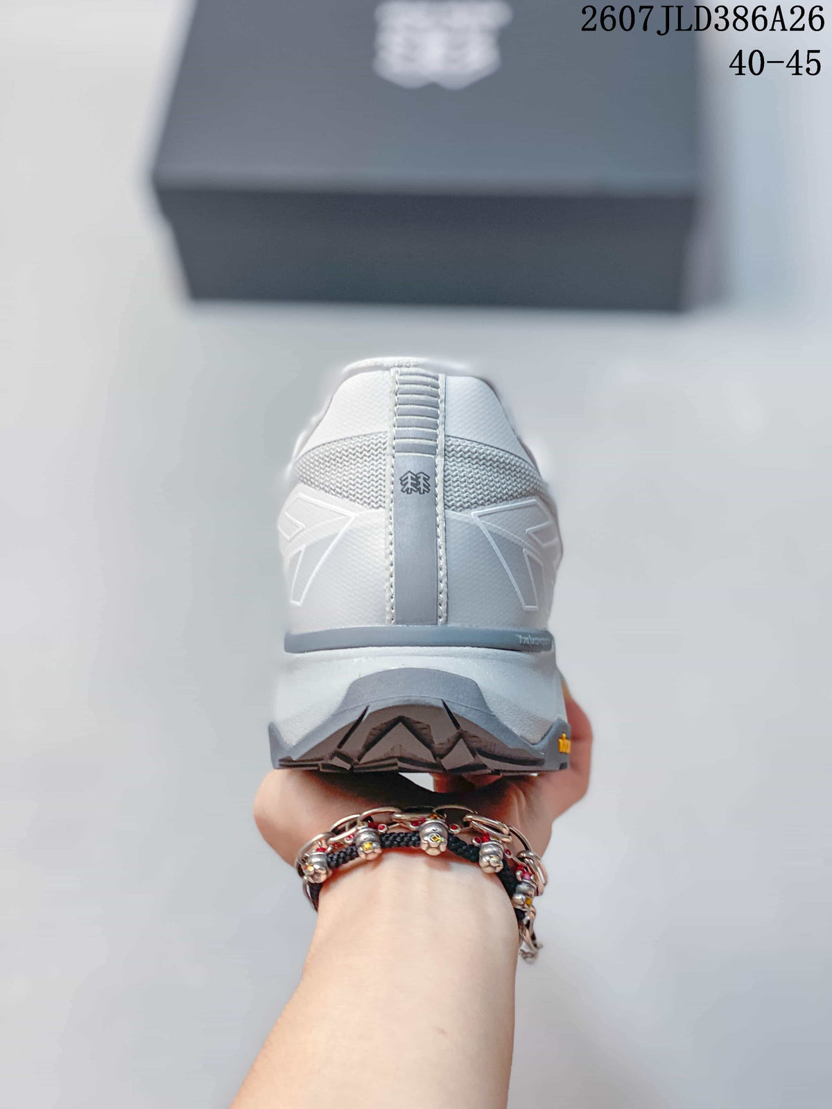 Rear view of the white and light-gray sneaker showing the padded heel, central pull detail, layered outsole, and tread.