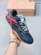 Angled side view showing the black sneaker, red accents, burgundy heel detail, white laces and gum outsole.