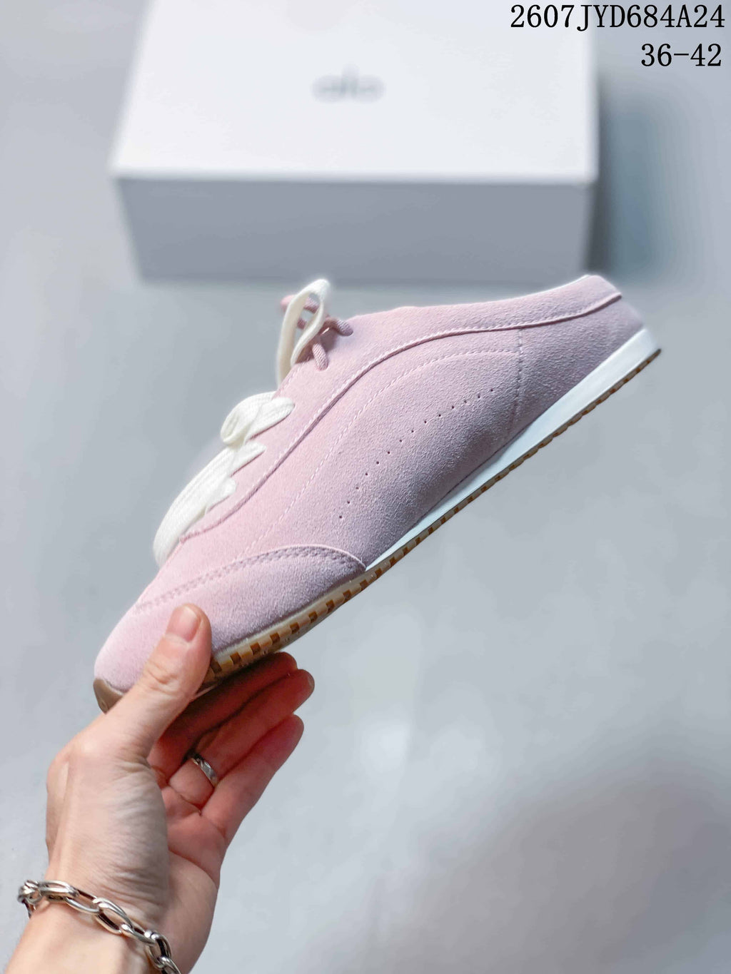 Side view of the pink low-top sneaker showing stitched panels, a rounded toe, and white midsole.