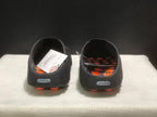 Rear view of the black slides showing open heels, orange outsole pods, and Nike heel badges.