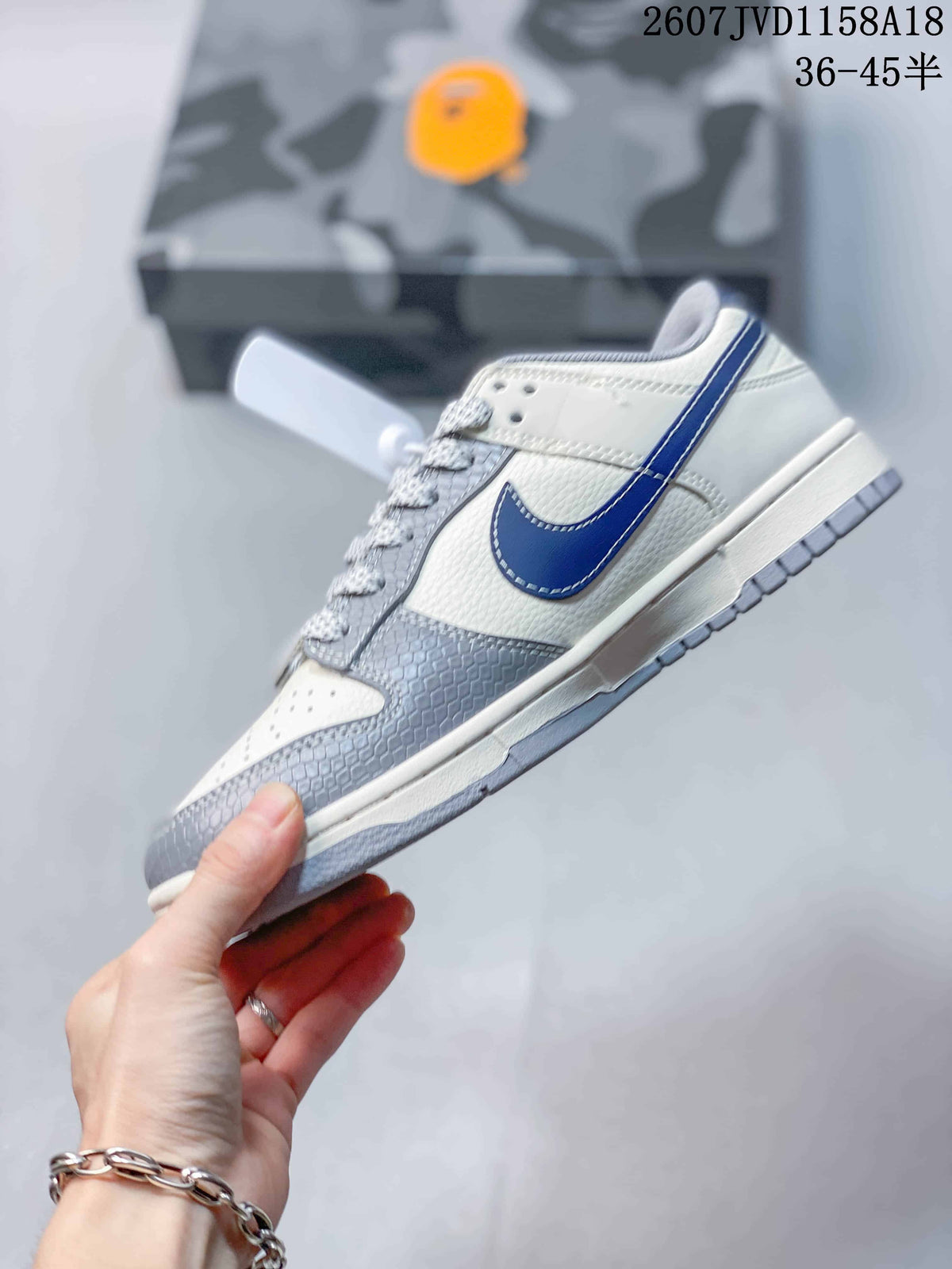Side profile showing the cream upper, gray overlays, blue Swoosh, and gray outsole.