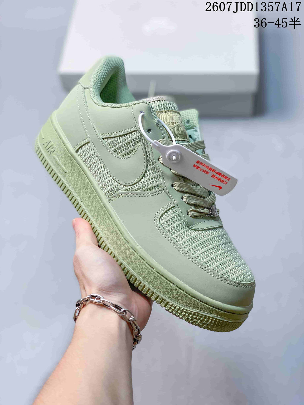 Angled side view of the pale green Nike sneaker showing the swoosh, woven panels and attached product tag.