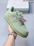Angled side view of the pale green Nike sneaker showing the swoosh, woven panels and attached product tag.