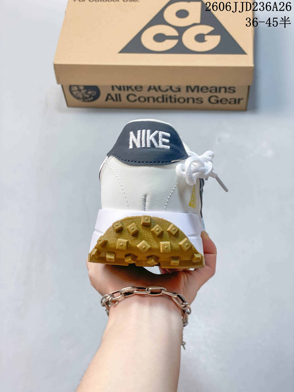 Rear view of a white Nike ACG sneaker showing the dark heel panel, padded collar, and gum-colored outsole.