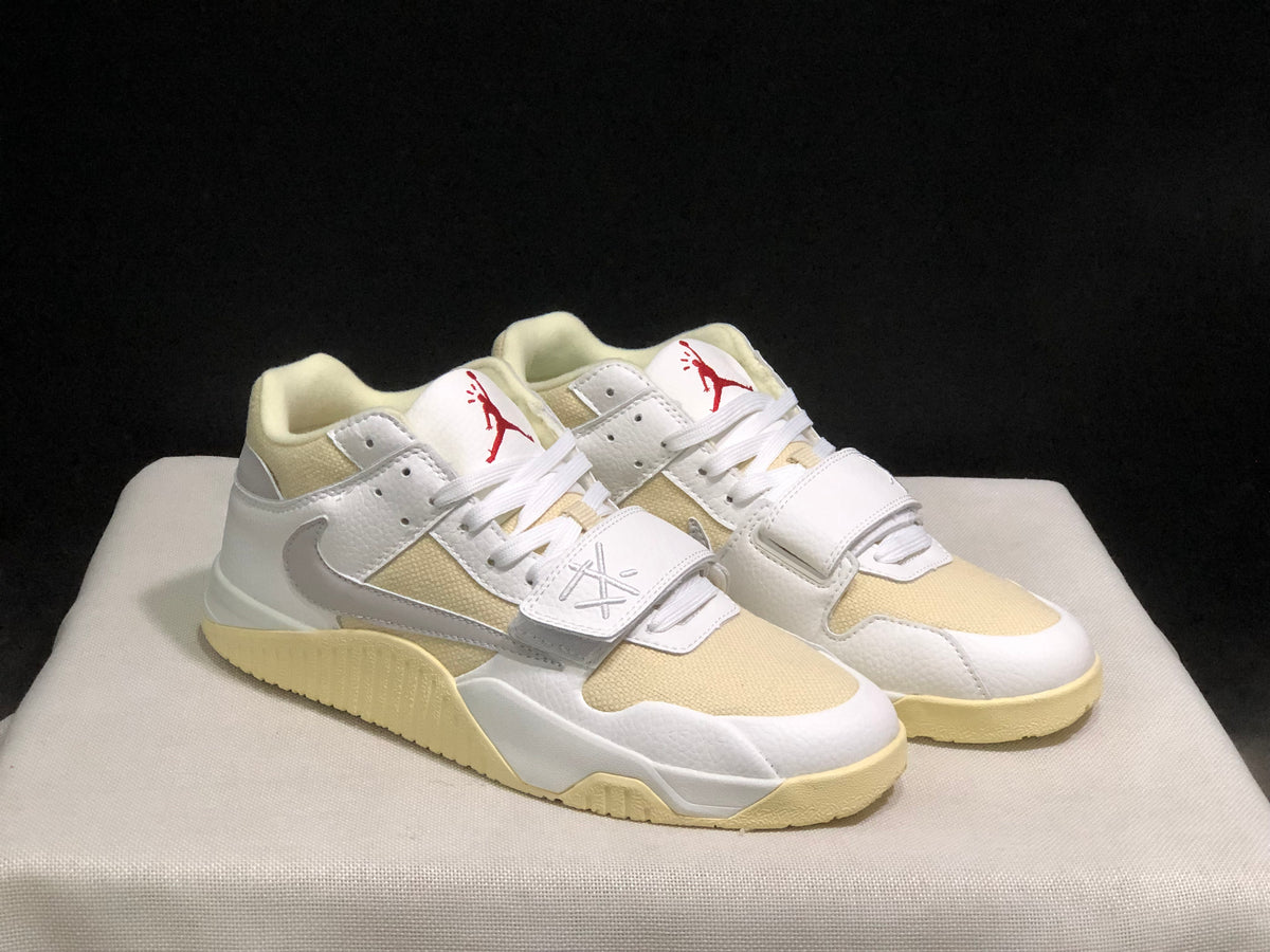 Pair of sneakers in a front three-quarter product view with white uppers, cream panels and red accents.