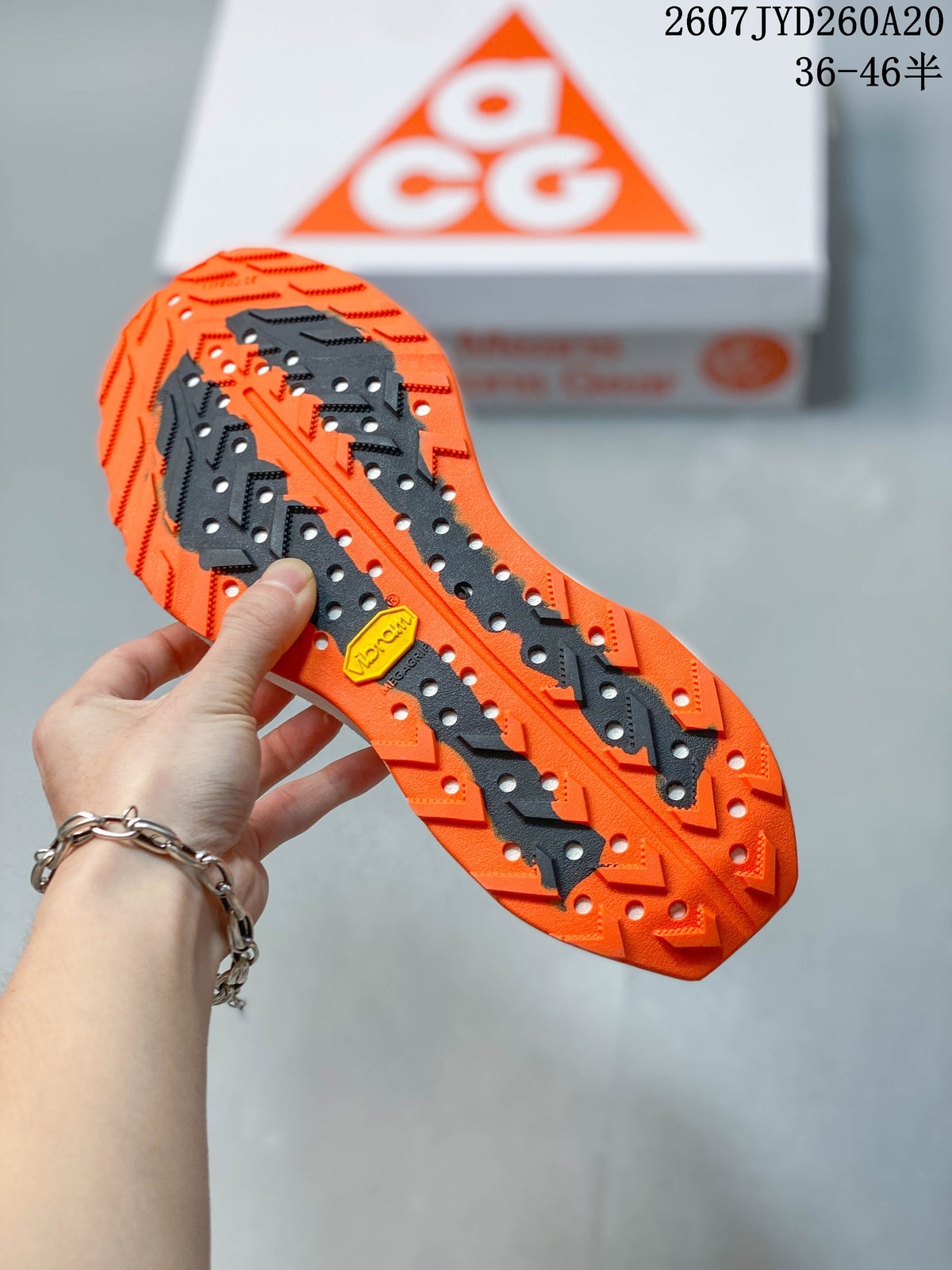Close-up of the orange and black lugged outsole on a Nike ACG Ultrafly Trail sneaker.