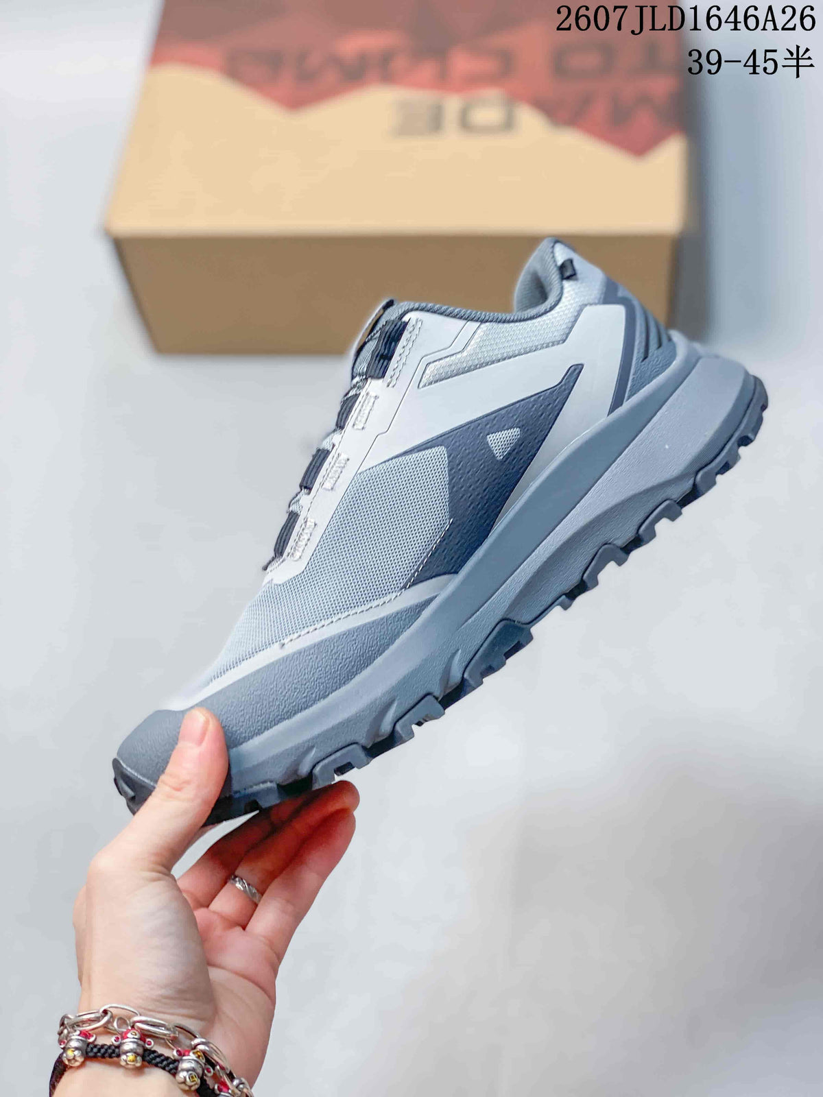 Side view of the gray and white low-top hiking shoe showing mesh-style panels, overlays, and a lugged sole.