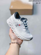 Angled side view of the white sneaker showing the side logo, lace-up construction, and segmented outsole.