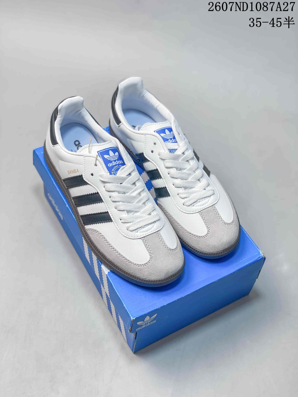 Pair of white adidas Originals Samba ADV sneakers with black side stripes displayed on a blue shoebox.