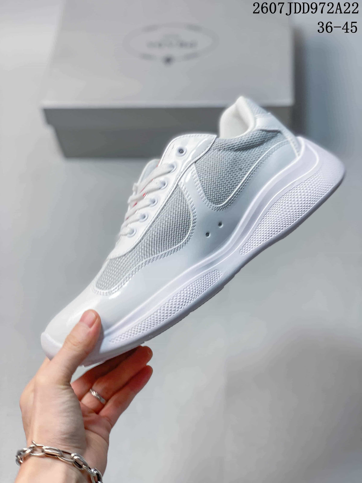 Side view of the white low-top sneaker showing glossy panels, gray mesh-style inserts, and the textured white sole.