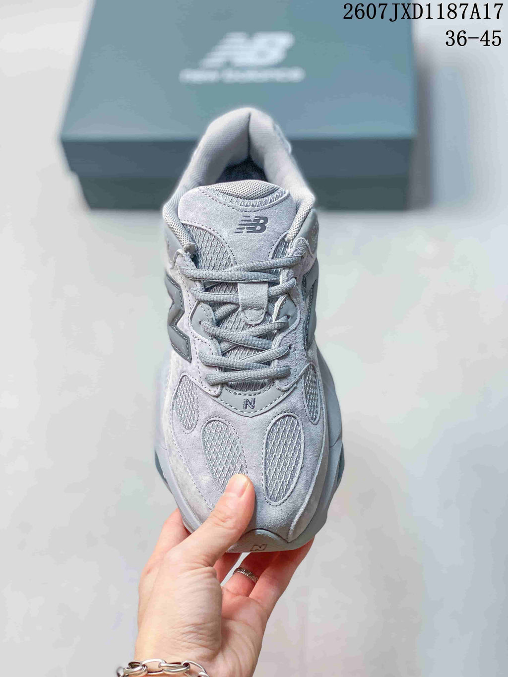 Front view of the grey lace-up sneaker showing the padded tongue, oval mesh panels, and New Balance branding.