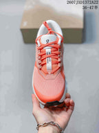Top view of a coral and white lace-up running sneaker showing the patterned upper and tongue branding.