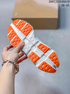Underside view of an orange and white sneaker showing the patterned outsole tread and sculpted midsole.