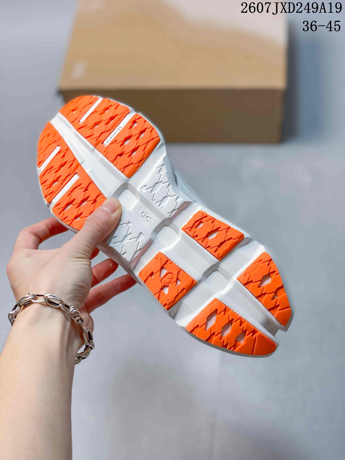 Underside view of an orange and white sneaker showing the patterned outsole tread and sculpted midsole.