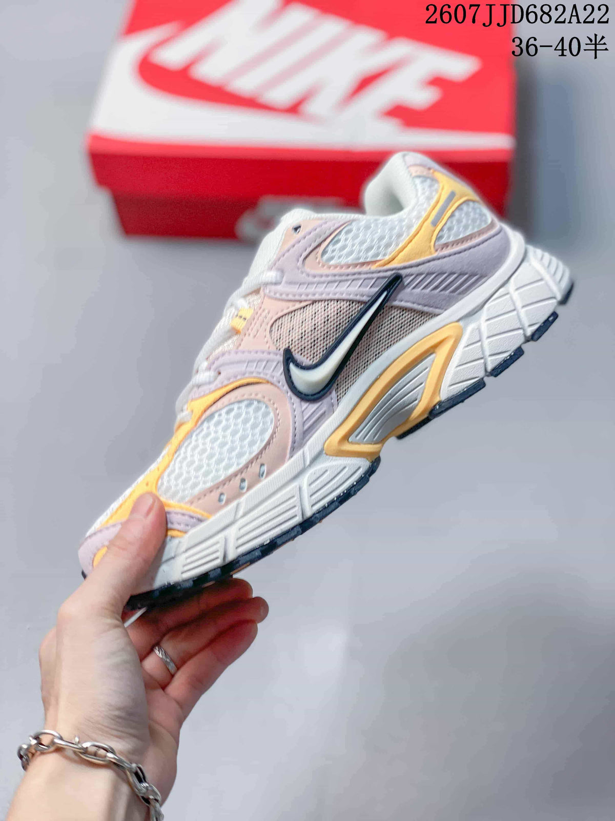 Side profile of the Nike V5 RNR sneaker showing the large side Swoosh, layered pink and yellow panels, and raised midsole; image text shows style code 2607JJD682A22 and size range 36–40.