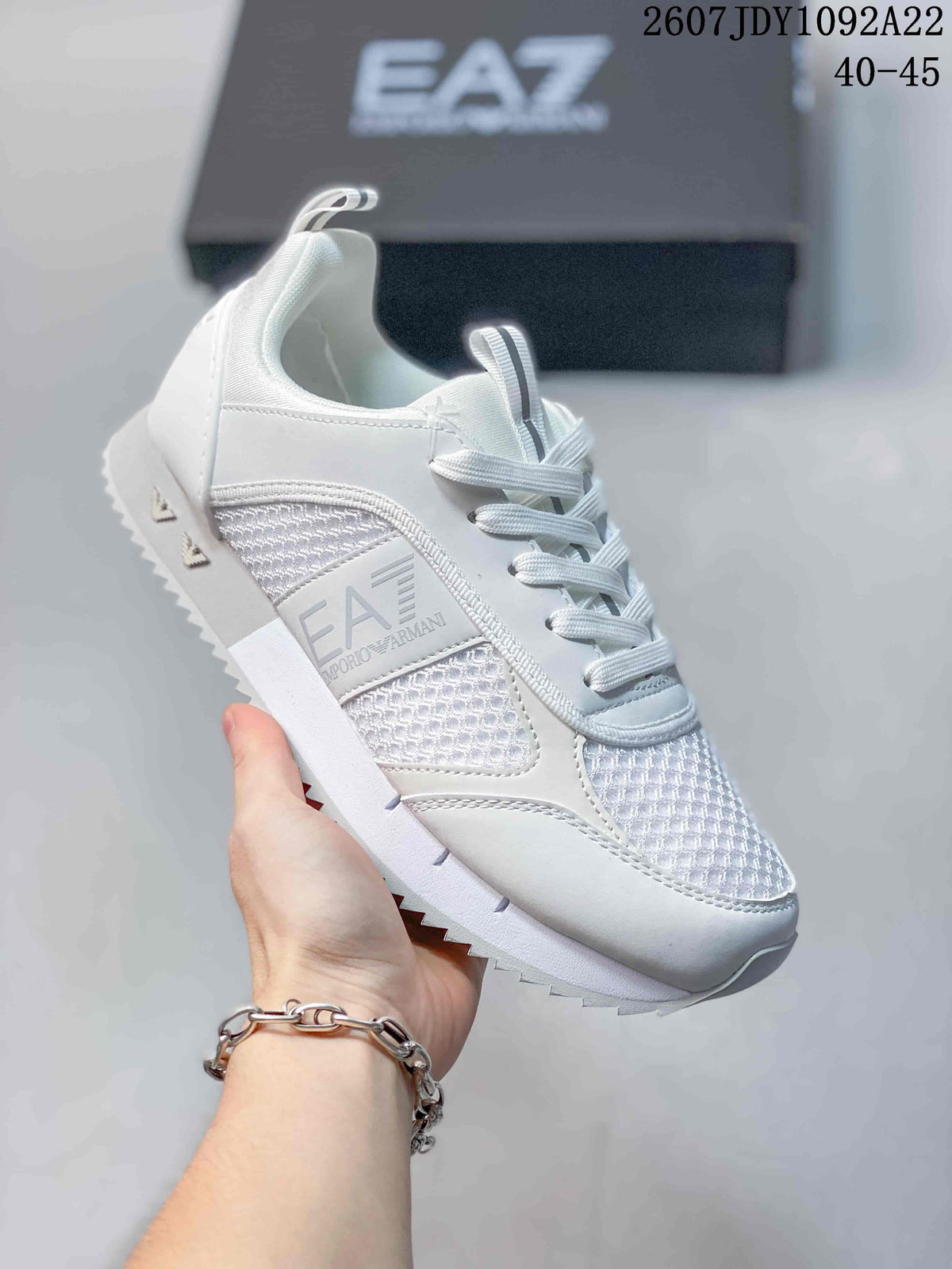 Close-up of a white EA7 sneaker showing the side branding, textured mesh-style inserts and lace-up front.