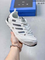 Angled side view of the white sneaker showing layered panels, dark side accents and metallic-tone details.