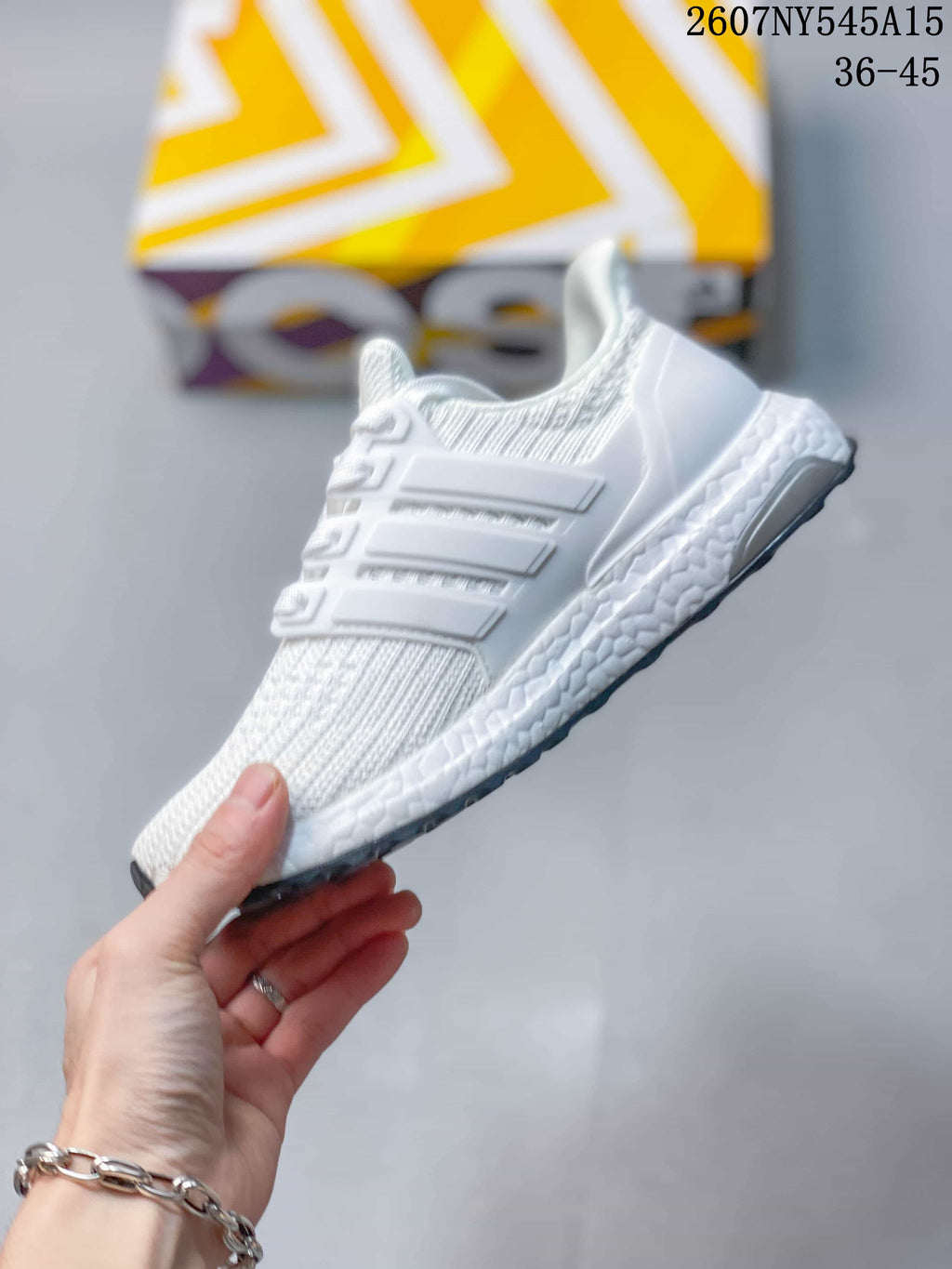 Side profile of a white Adidas Ultraboost Light sneaker showing the layered side cage, knitted upper and textured midsole.