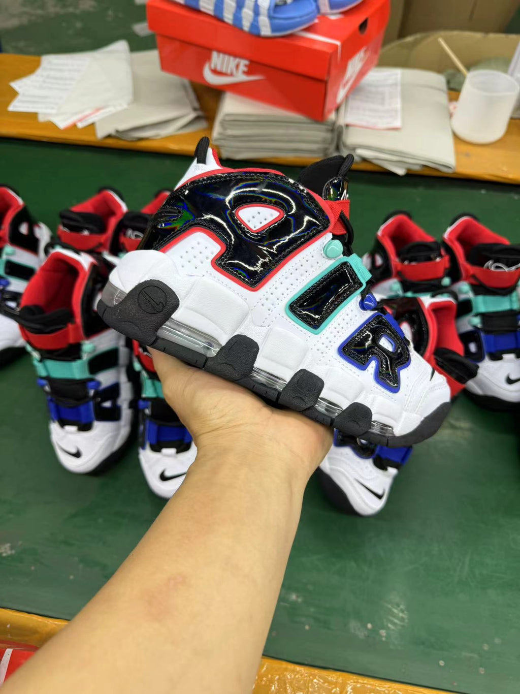 Sneaker held in hand against a background of similar white, black, and multicolor-accented shoes