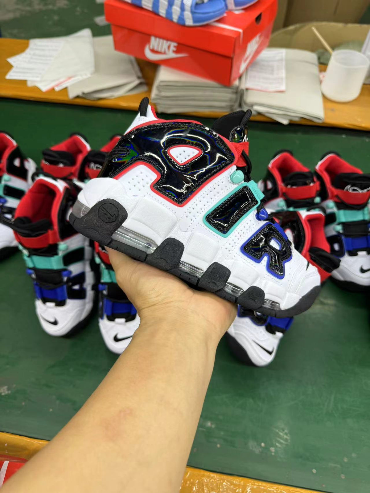 Sneaker held in hand against a background of similar white, black, and multicolor-accented shoes