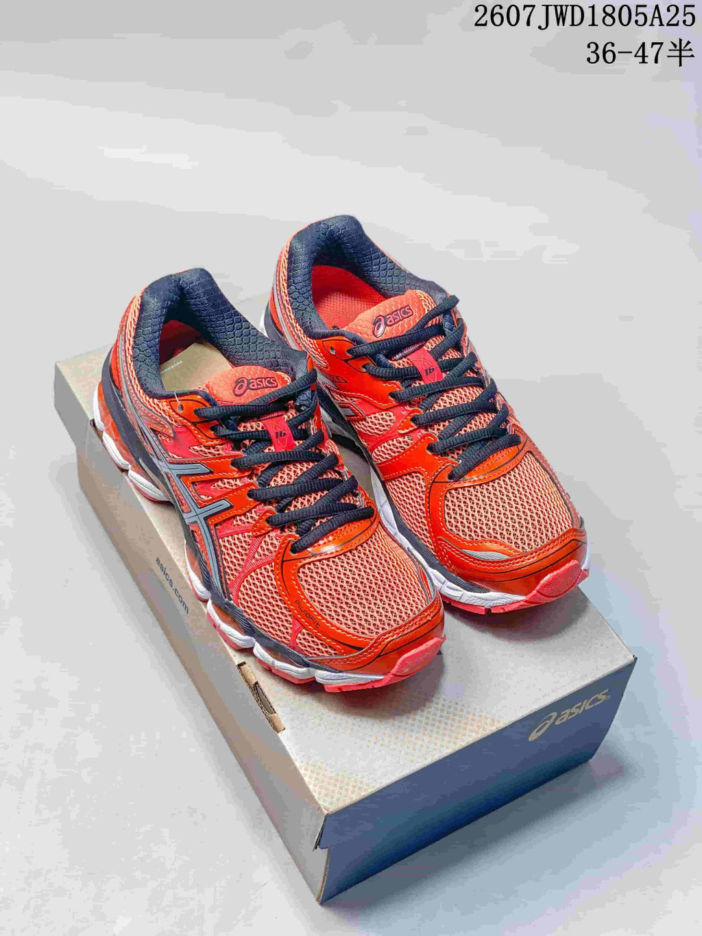 Pair of red and orange ASICS Gel-Nimbus 16 running shoes with black details displayed on an ASICS shoebox.
