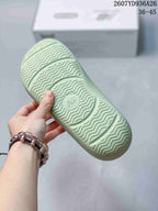 Close-up of the pale green sandal outsole showing a wavy traction pattern and central embossed branding.