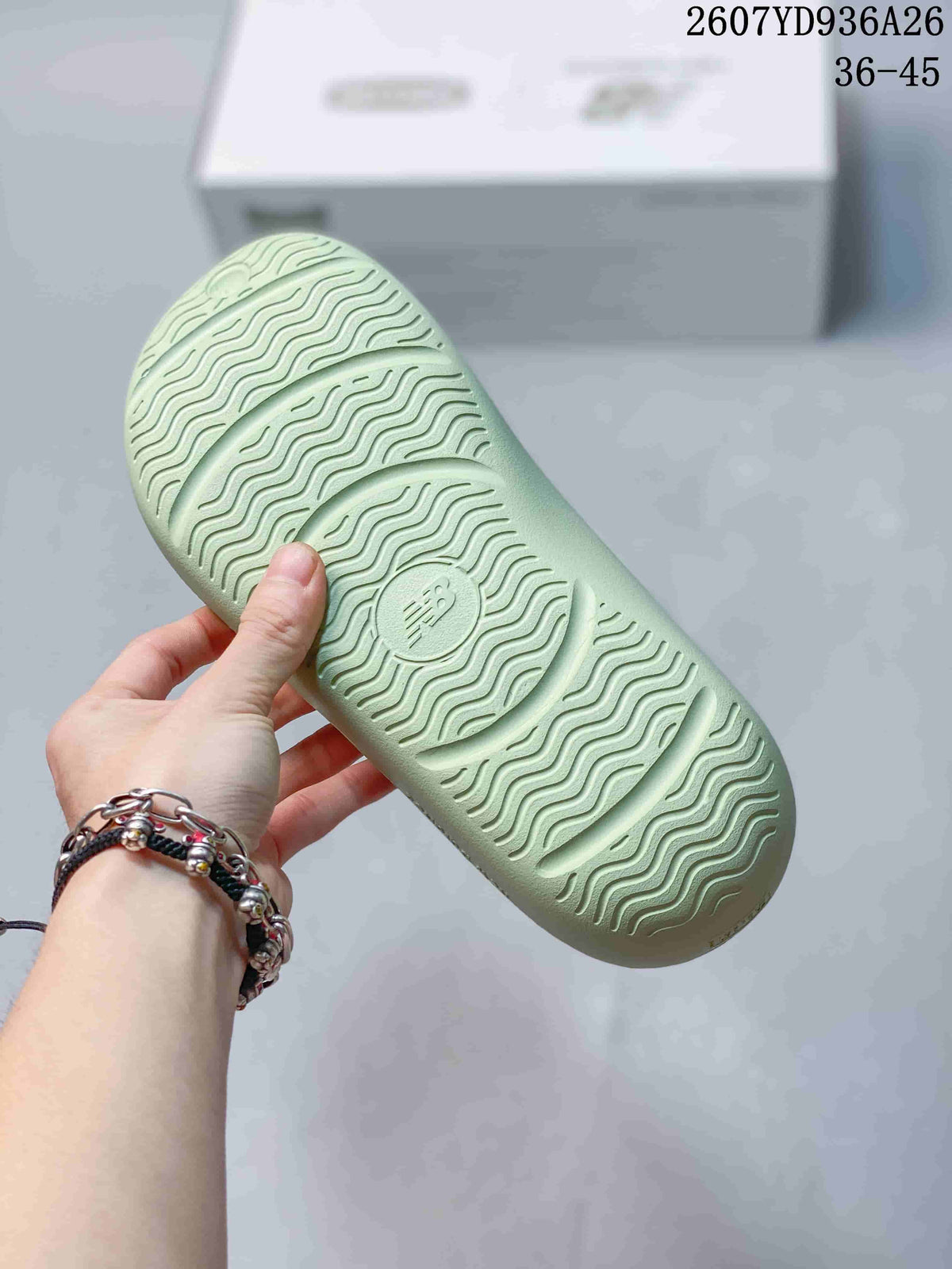 Close-up of the pale green sandal outsole showing a wavy traction pattern and central embossed branding.