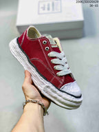 Angled side view of a red MMY sneaker with white laces, contrast stitching and a sculpted white sole; image text shows style code 2506JXD320A29 and size range 36–45.