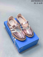 Pink metallic adidas Samba Jane sneakers with adjustable straps displayed on a blue shoebox.