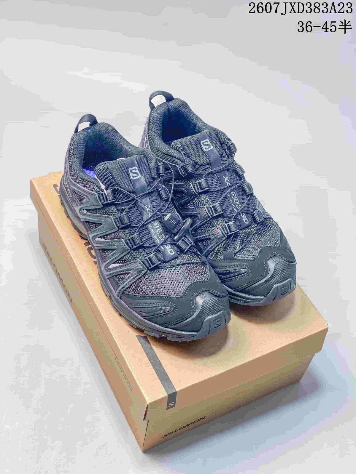Pair of gray Salomon XA Pro 3D low-top sneakers displayed on a Salomon shoe box; mesh panels, layered supports, and lugged outsoles are visible.