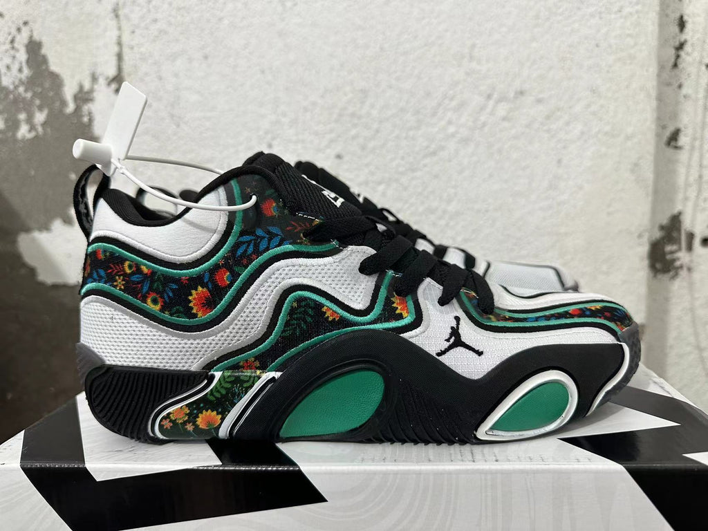 Side view of a Jordan basketball shoe with white panels, green accents, and multicolor floral detailing.