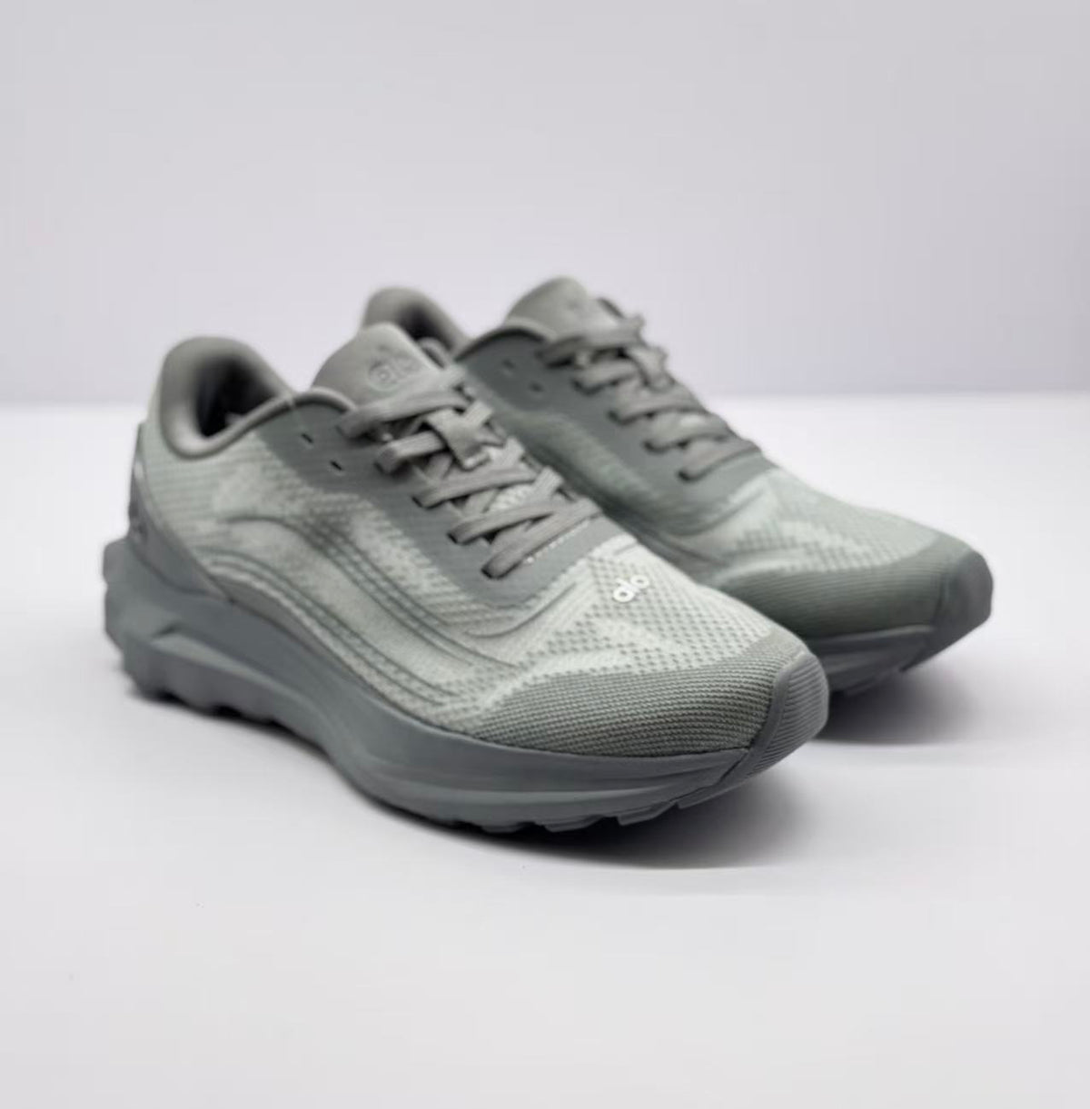 Three-quarter front view of a pair of gray Alo Runner sneakers with visible tongue and toe branding.