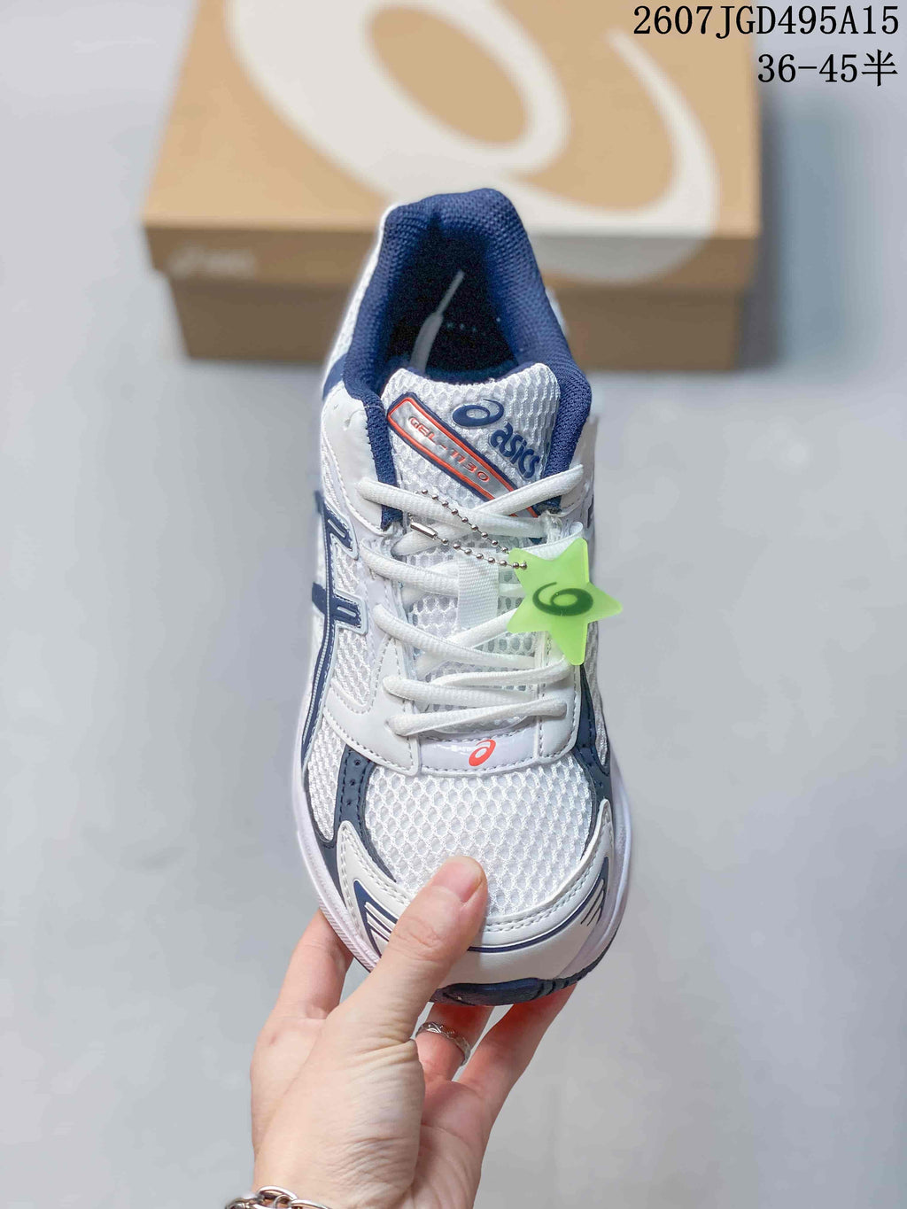 Top view of the white and navy ASICS GEL-1130 sneaker with white laces, mesh-style toe panel and green hangtag.