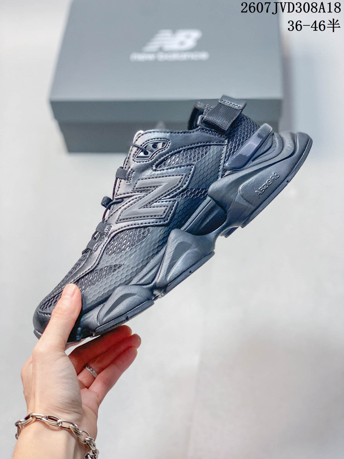 Side profile of a dark grey New Balance 9060 sneaker showing the large N logo, layered upper and sculpted sole.