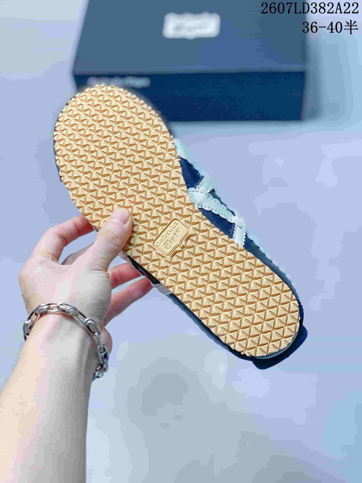 Underside view of the sneaker showing the gum-colored outsole and repeating patterned tread.