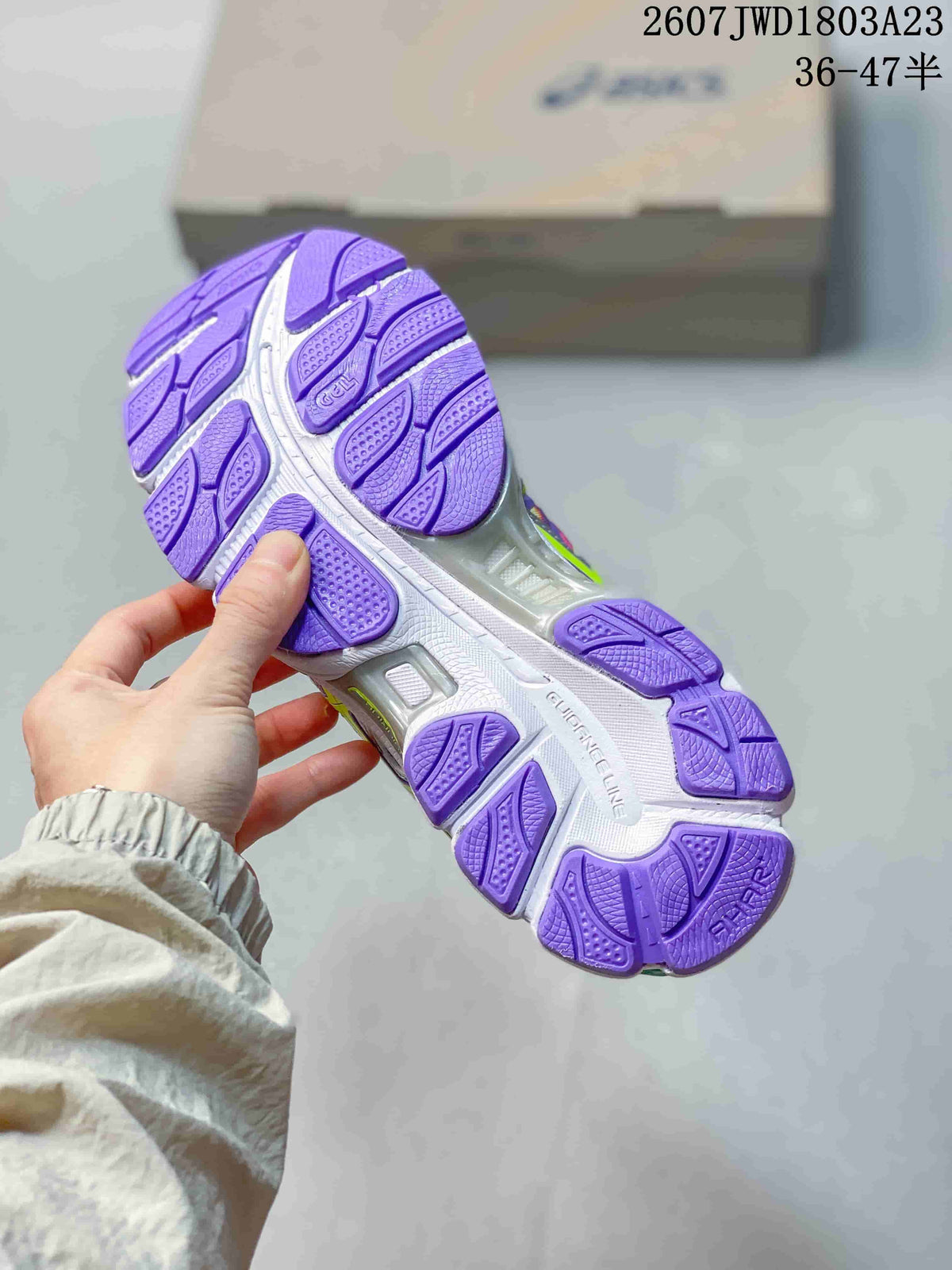 Underside view of an ASICS sneaker showing the segmented purple-and-white outsole tread.