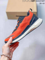 Side profile of an orange and navy ECCO sneaker showing the textured upper, dark overlays, lacing, and layered sole.