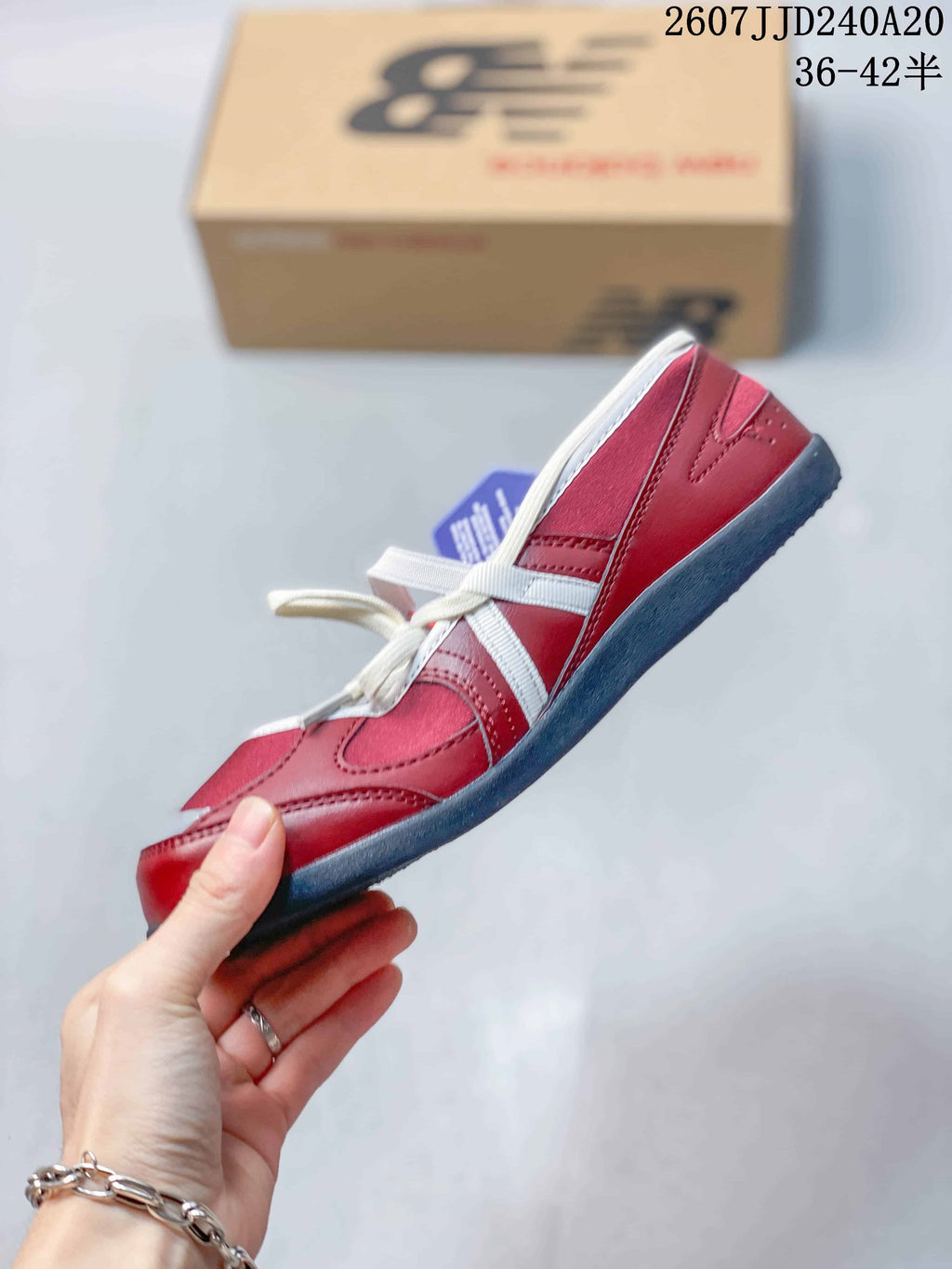 Side view of the red sneaker showing white contrast panels, layered stitching, white laces, and a dark low-profile outsole.