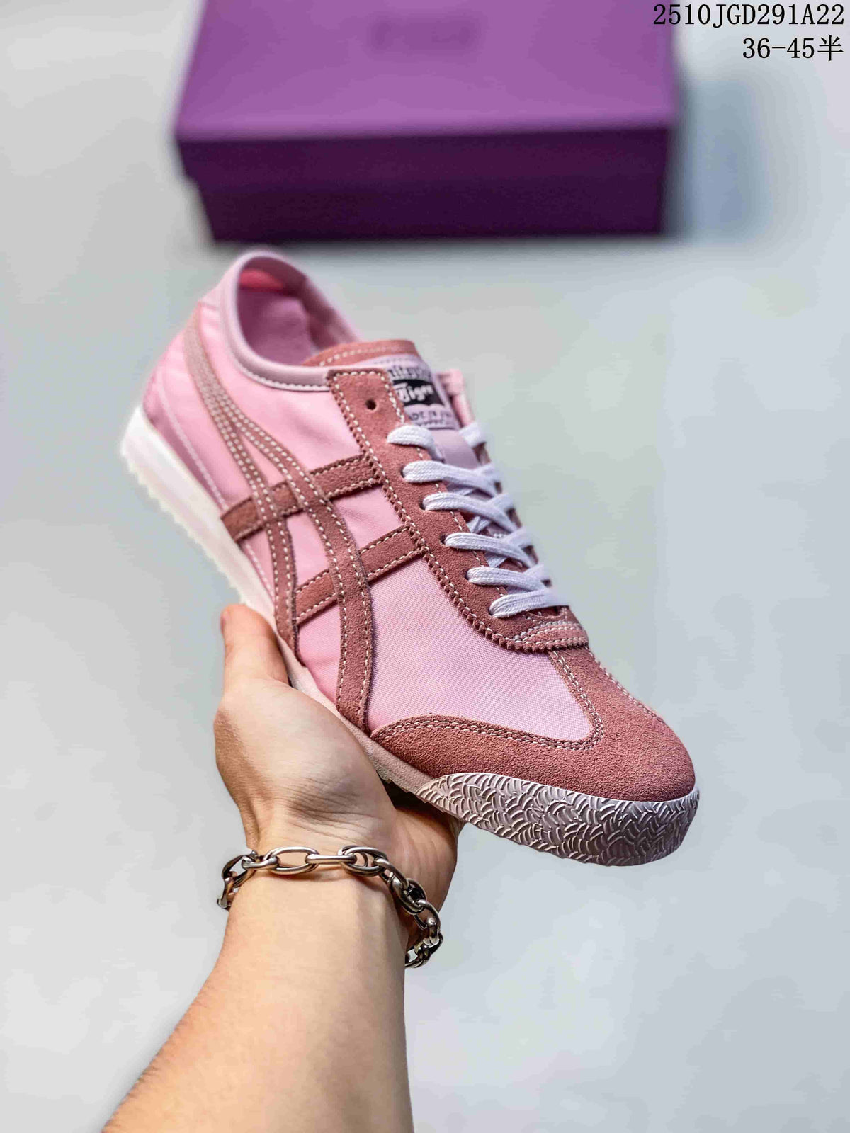 Pink and mauve Onitsuka Tiger sneaker held in hand, showing tonal contrast stripes and stitched detailing.