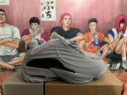 Side profile of a grey sneaker with sculpted panels and glossy black accent