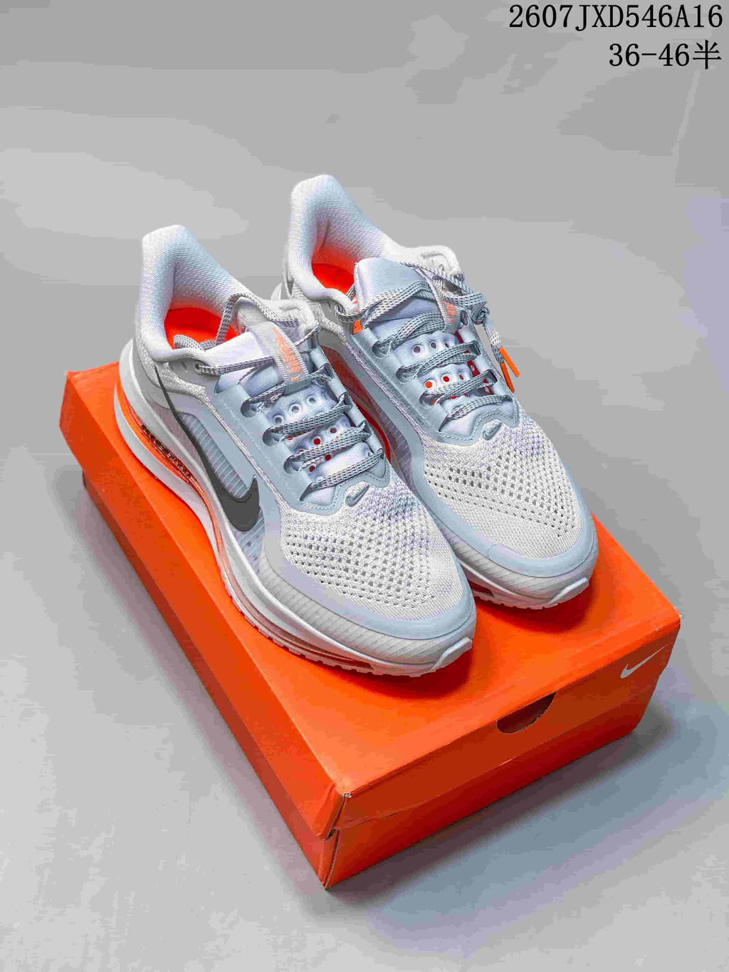Pair of white and gray Nike sneakers with orange accents displayed on an orange shoebox; overlay text shows style code 2607JXD546A16 and size range 36–46.5.